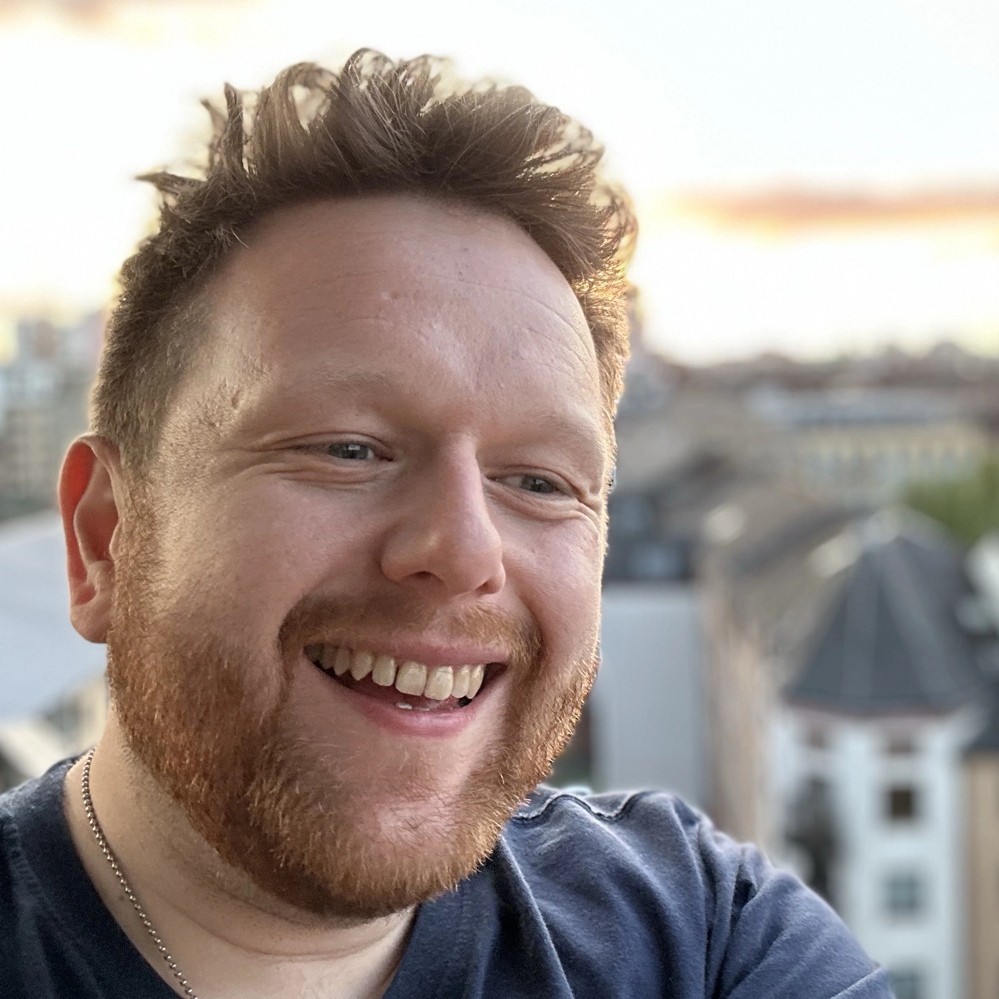 Paul laughs at something on a balcony with the City of Glasgow behind him.